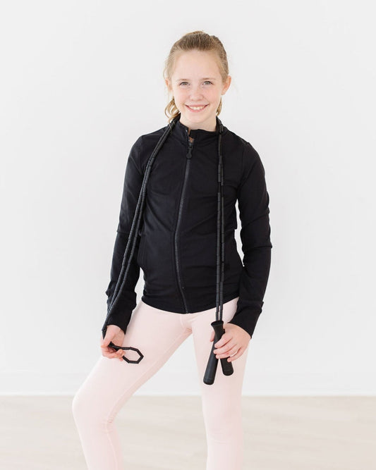 Person wearing a black jacket and pink leggings holding a jump rope on a white background