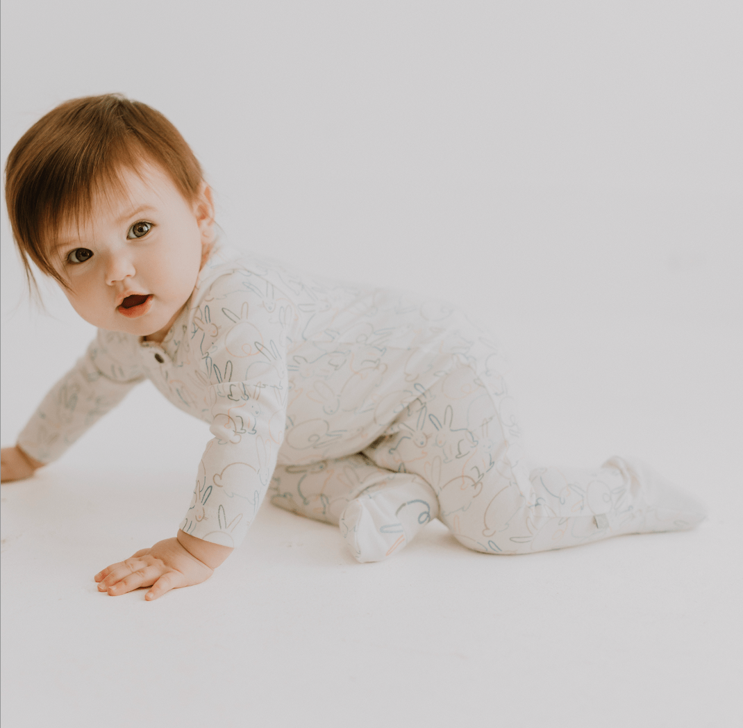 Baby in a patterned onesie crawling on a white surface