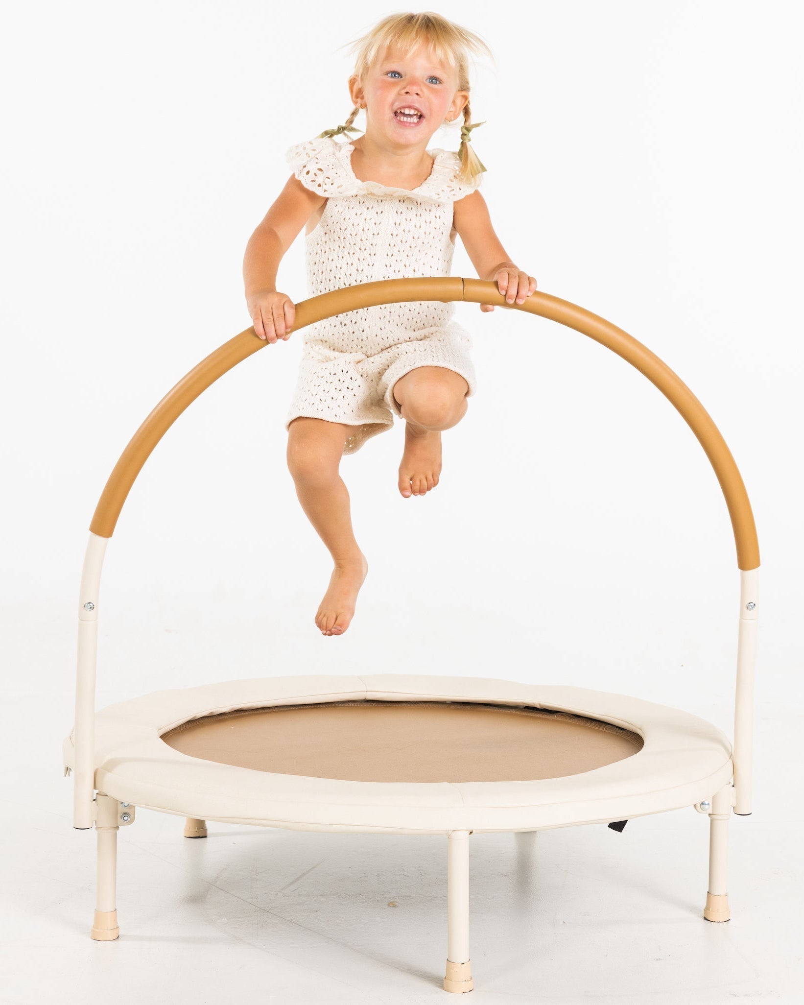 Child jumping on a small trampoline with a white background