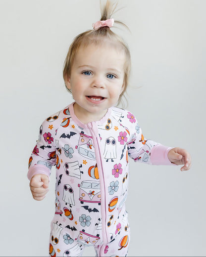 Child wearing a colorful onesie with cartoon designs on a plain background