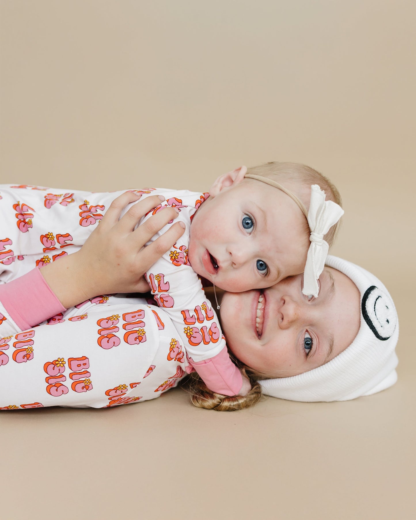 Two children wearing pajamas and headbands on a beige background