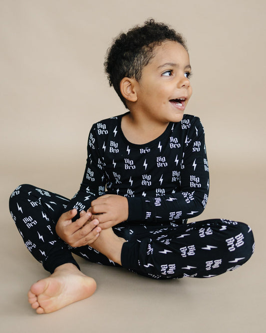 Child wearing black pajamas with white patterns on a beige background