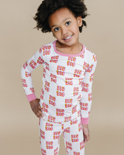 Child wearing a white pajama set with colorful text on a beige background