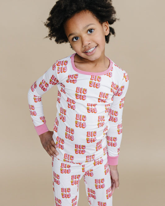 Child wearing a white pajama set with colorful text on a beige background