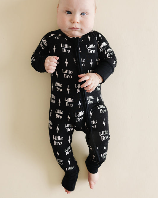 Baby wearing a black onesie with text and star patterns on a beige background