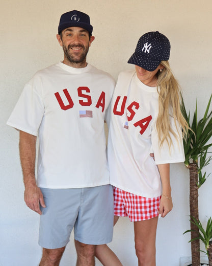 Two people wearing 'USA' t-shirts and baseball caps standing next to each other.
