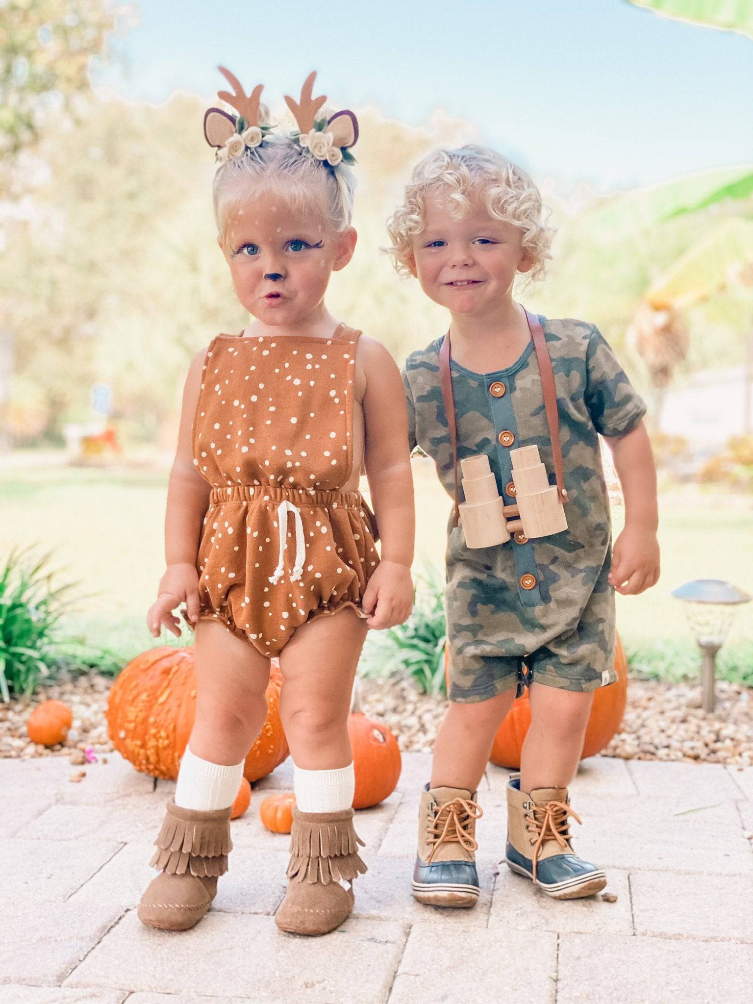 Two children in autumn-themed outfits with pumpkins in the background