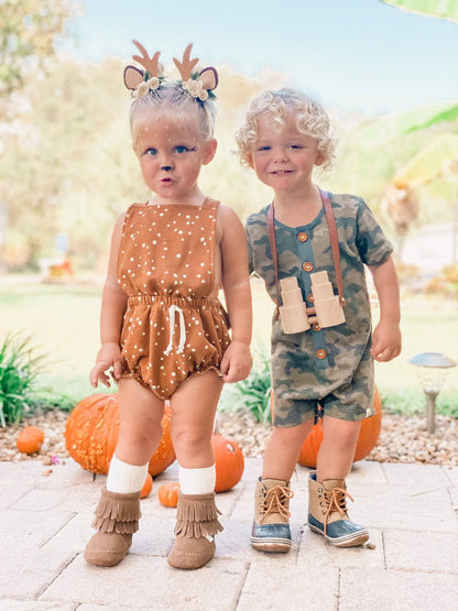 Two children in autumn-themed outfits with pumpkins in the background