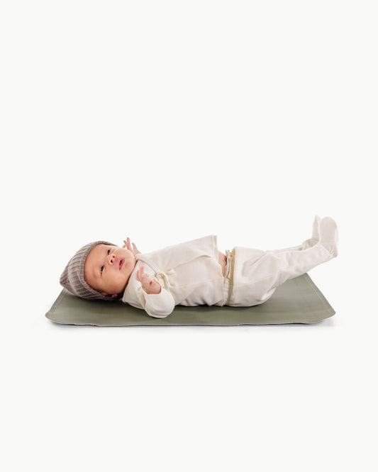 Baby lying on a green mat with a white background