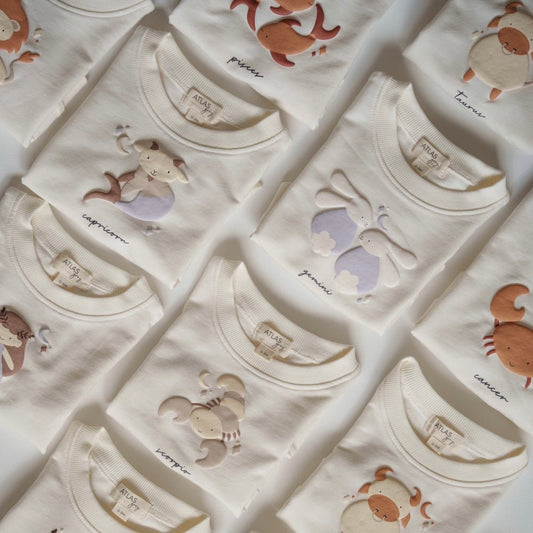 Collection of baby onesies with zodiac signs on a white background